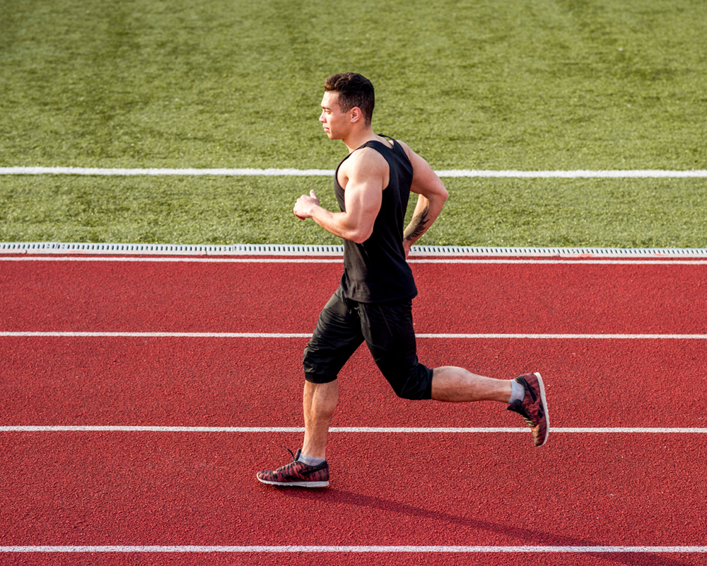 muscular-male-runner-running-red-race-track